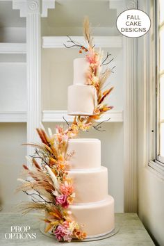 three tiered wedding cake decorated with flowers and feathers