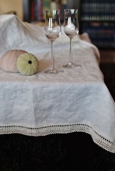 two wine glasses sitting on top of a table next to a sea urchin and a seashell