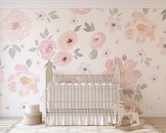 a baby's room with pink flowers on the wall and a white crib