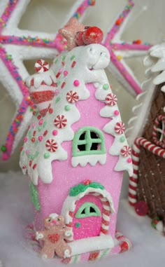 a small pink house with snow on the roof and decorations around it's base