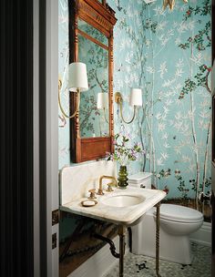 a bathroom with blue wallpaper and gold fixtures in the sink, toilet and mirror