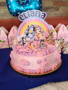 a birthday cake with pink frosting and cartoon characters on it, surrounded by other decorations