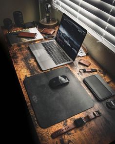 an open laptop computer sitting on top of a wooden desk next to a mouse pad