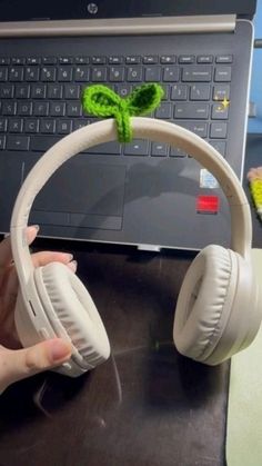 a person is holding headphones in front of a laptop with a green leaf on it