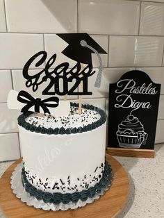 a cake with a graduation cap and tassels on top sits in front of a sign that reads class 2012