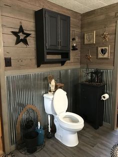 a white toilet sitting inside of a bathroom next to a trash can and wooden walls