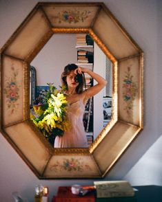 a woman is taking a selfie in front of a mirror with flowers on it