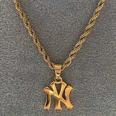 A classic New York pendant design featuring a 3mm luxe rope chain.  Shower, workout or swim - this chain does not tarnish.  Materials: 18K Gold Plated / Stainless Steel Chain Length: 45cm or 50cm Chain Thickness: 3 mm Hypoallergenic / Tarnish-Free Gold Men Jewelry, 90s Gold Jewelry, Yankees Necklace, Gold Jewelry Men, Jewelry Street Style, Ny Necklace, Jewelry Accessories Necklaces, Shower Workout, Gold Necklace Stack