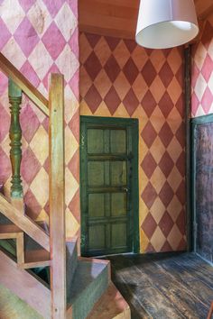 the stairs lead up to an open door in a room with pink and green tiles on the walls