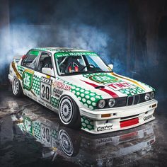 a white car with green and red designs on it's hood is parked in front of a black background