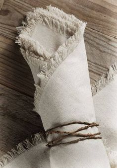 two pieces of white linen tied together with twine on wooden floor next to wood planks