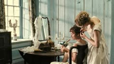 two women are sitting in front of a mirror and one is combing the other's hair