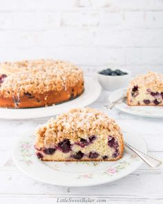 a blueberry crumb cake on a plate with two slices cut out and ready to be eaten