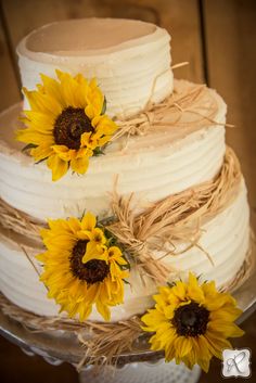 a three tiered cake with sunflowers on the side and burlap