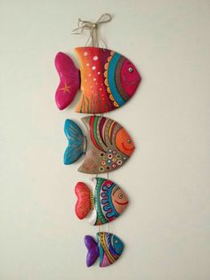 three colorful fish hanging on a white wall