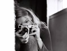 a woman taking a selfie in front of a mirror while holding a camera up to her face