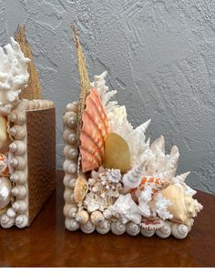 two decorative seashells are sitting on a table next to each other and one is made out of shells