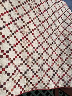 a large white and red quilt on top of a fence