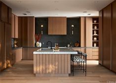 a large kitchen with wooden cabinets and marble counter tops, along with bar stools