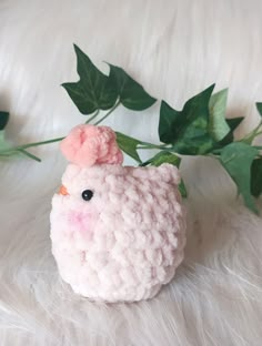 a stuffed animal with a pink flower on its head sitting next to some green leaves