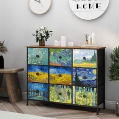 a sideboard with paintings on it in front of a wall clock and vases