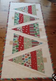 the table runner is made up of strips of fabric and has christmas trees on it