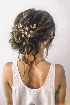 the back of a woman's head wearing a white tank top with flowers in her hair