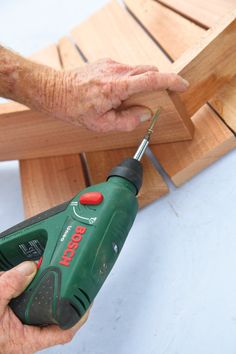 a person using a cordless drill to attach a piece of wood on a bench