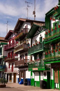 several balconies are painted green and white with flowers on the balconies