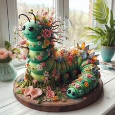 a very cute looking cake made to look like a caterpillar with flowers on it