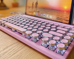 a pink computer keyboard sitting on top of a wooden desk