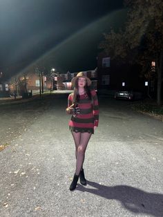 a woman is standing in the middle of an empty street at night with her hat on