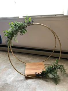 a wooden box sitting on the floor next to a metal ring with plants growing out of it