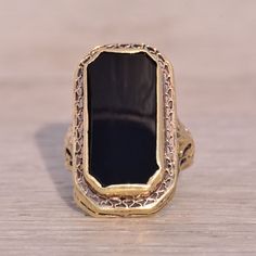 This Stunning Piece, Known As The Art Deco Elegance, Features A Captivating Elongated Emerald Cut Onyx Tablet At Its Center. The Rectangular Cut Onyx Is Elegantly Bezel Set In 14 Karat Yellow Gold, Designed With Intricate Filigree Detailing That Adds A Touch Of Vintage Sophistication Which Continues Down The Shank. The Ring Is Crafted In 14 Karat Yellow Gold And Is Currently A Finger Size 2.75 But Can Be Adjusted To Any Finger Size For An Additional Charge Upon Request, Ensuring A Perfect Fit. Onyx Signet Ring, Filigree Ring, Art Deco Era, Signet Ring, Bezel Setting, Womens Jewelry Rings, Emerald Cut, Black N Yellow, Onyx