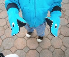 a little boy in a blue jacket with a stuffed animal on his arm and feet