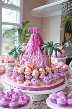 a table topped with cupcakes and cakes covered in pink frosted icing