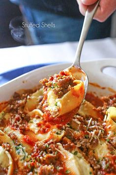 a close up of a spoon full of pasta with meat and sauce in a bowl