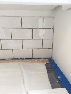 a room that has some white tiles on the wall and blue tape around the floor