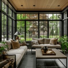 a living room filled with lots of furniture next to tall glass windows on the wall