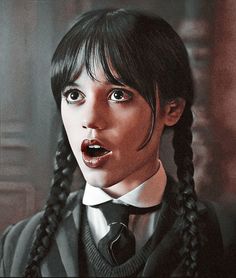 a woman with long black hair wearing a suit and tie, making a surprised face