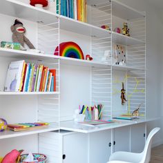 a room with white shelves filled with books and toys