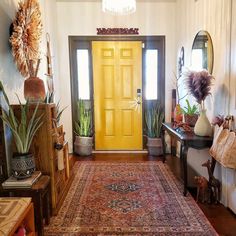 a yellow door is in the middle of a room with many potted plants and rugs