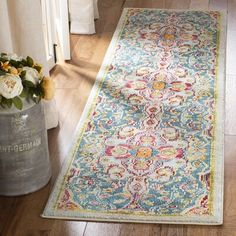 a colorful rug on the floor next to a vase with flowers in it and an open door