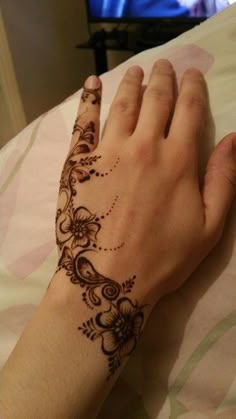 a woman's hand with a henna tattoo on her left arm and wrist