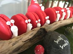 red macaroons are lined up in a row on a wooden board with white decorations