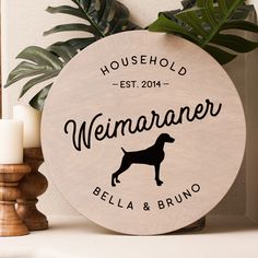 a wooden sign with a dog on it next to candles and a potted plant