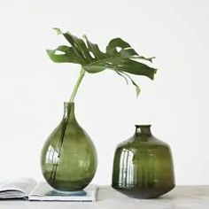 two green vases sitting next to each other on top of a white countertop