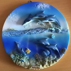 two dolphins swimming in the ocean on a blue glass wall hanging ornament with corals and seaweed