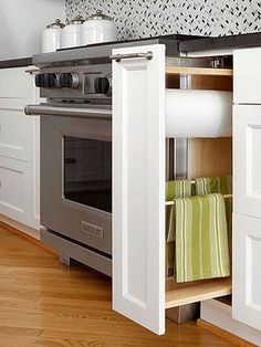 an open cabinet in the middle of a kitchen with white cabinets and stainless steel appliances