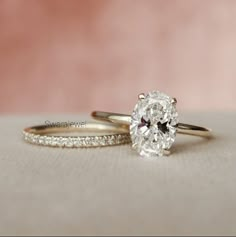 two gold wedding rings with an oval cut diamond on the side and pave band